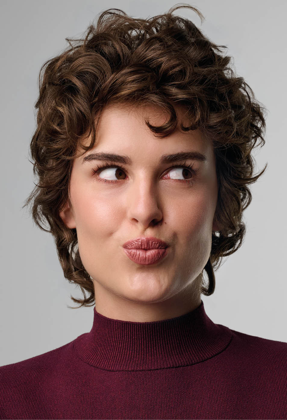 Persona con cabello rizado corto y su ter de cuello alto color vino que mira hacia un lado con expresi n pensativa. Descripci n generada con IA