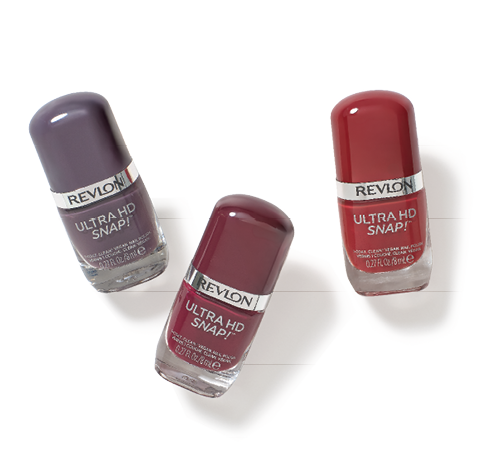 Tres frascos de esmalte de u as Revlon Ultra HD Snap en tonos morados y rojo oscuro sobre fondo blanco. Descripci n generada con IA
