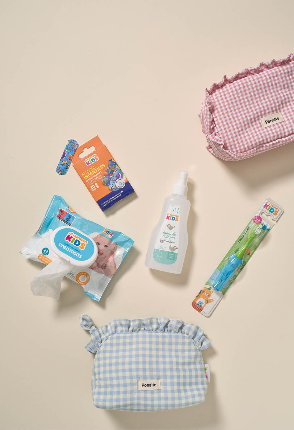 Dos estuches de tela con dise o de cuadros y varios productos para ni os como toallitas h medas, un cepillo de dientes, un spray y una curita sobre una superficie clara. Descripci n generada con IA