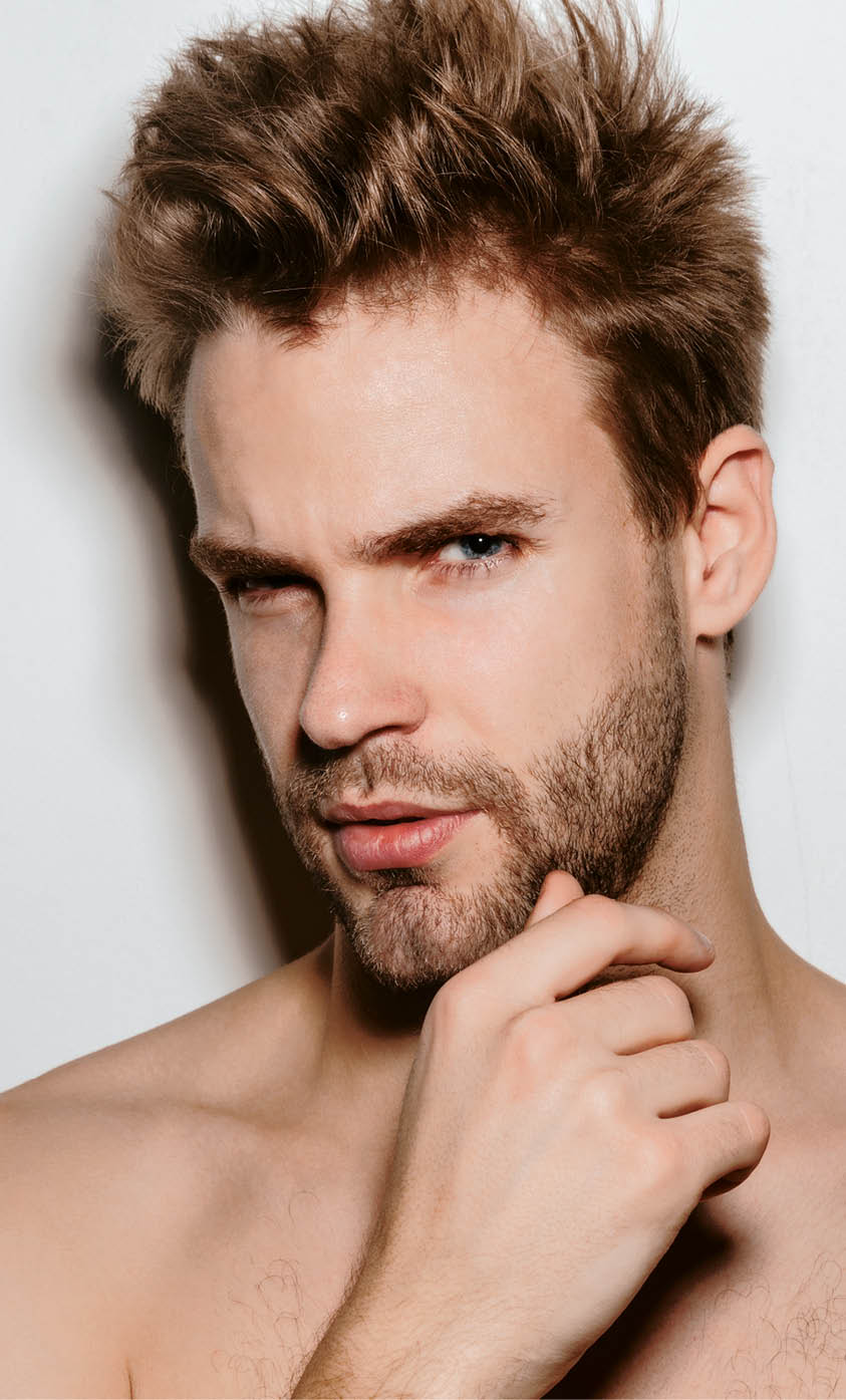 Handsome shirtless seductive young man posing isolated over white background, looking at camera