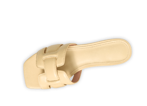 Sandalia beige de tac n bajo con dise o abierto y detalle en forma de H en la parte superior. Descripci n generada con IA
